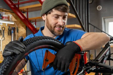 Sakallı Msn Ustası modern düzenekle organize garajda bisiklet çarkını tamir ediyor.