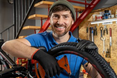 Sakallı tamirci modern atölyede bisiklet lastiğini tamir ediyor.