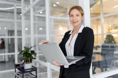 Ofiste. Beyaz, güzel görünümlü, dizüstü bilgisayarı olan bir kadın.