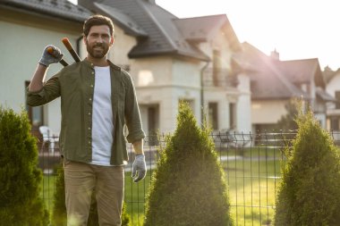 Bahçede çalışıyorum. Kendine güvenen genç sakallı adam bahçede konuşuyor ve kararlı görünüyor.