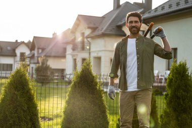 Bahçede çalışıyorum. Kendine güvenen genç sakallı adam bahçede konuşuyor ve kararlı görünüyor.