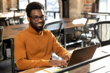 Ofiste. Ofiste çalışan, dizüstü bilgisayarı olan Afrikalı Amerikalı genç bir adam.