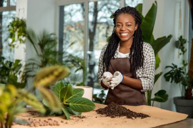 Çiçekçi. Memnun ve eğlenen genç bir kadın çiçek ekiyor ve meşgul görünüyor.