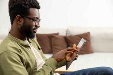 Evden çalışıyorum. Sakallı, genç, Afro-Amerikan bir adam. Evden çalışıyor ve olaya dahil olmuş gibi görünüyor.