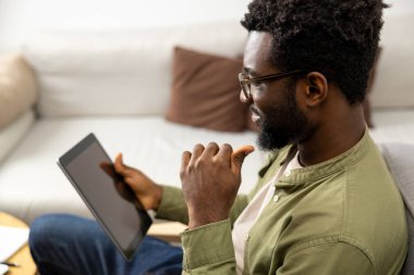 Evden çalışıyorum. Sakallı, genç, Afro-Amerikan bir adam. Evden çalışıyor ve olaya dahil olmuş gibi görünüyor.