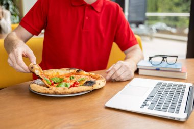 Pizzacıda. Pizzacı genç adam pozitif görünüyor ve pizza yemeye hazırlanıyor.