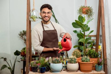 Kaktüsler. Çiçekçi asistanı kaktüsleri suluyor ve memnun görünüyor.