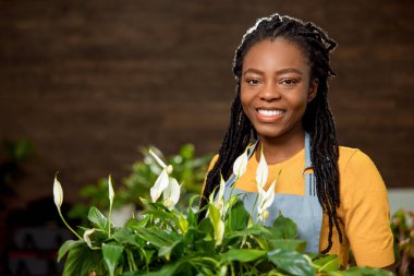 Çiçekçide çalışıyorum. Şirin gülümseyen çiçekçi yardımcısı mutlu görünüyor.