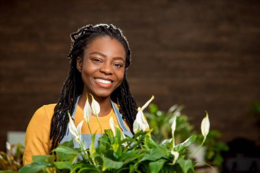 Çiçekçide çalışıyorum. Şirin gülümseyen çiçekçi yardımcısı mutlu görünüyor.