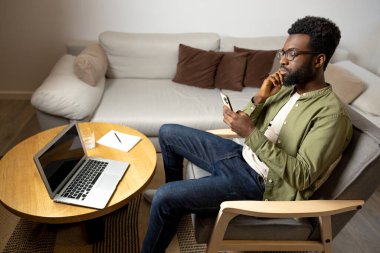 Çalışıyorum. Yuvarlak masada oturan ve dizüstü bilgisayarla çalışan genç bir adamın en iyi görüntüsü.