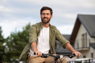 Kendinden emin genç adam. Bisikletli beyaz sakallı genç adam kendinden emin görünüyor.