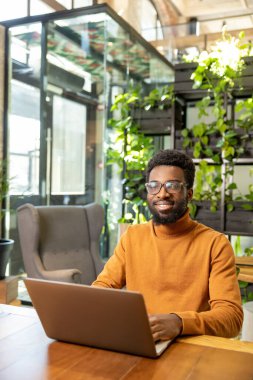 Afrika kökenli Amerikalı uzaktan kumandalı işçi tek başına çalışma masasında otururken içeriği geliştiriyor