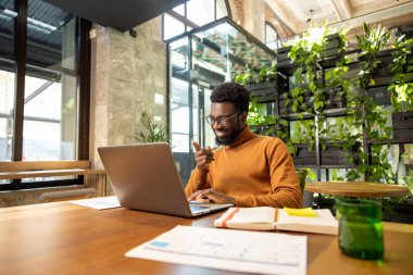 Yaratıcı ortamda masa başında otururken müşterileri yöneten uzak erkek danışman