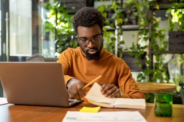 Gözlüklü bir adam, çağdaş teknoloji merkezinde dijital raporları inceliyor.