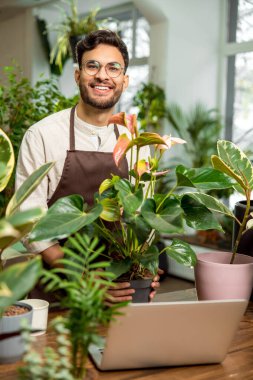 Çiçekçi. Çiçekçide gözlüklü genç adam mutlu ve gülümsüyor.