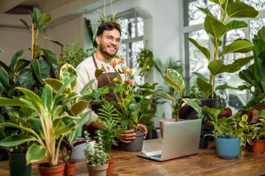 İş günü. Çiçekçide dizüstü bilgisayarda oturan genç adam.