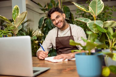 İş günü. Çiçekçide dizüstü bilgisayarda oturan genç adam.