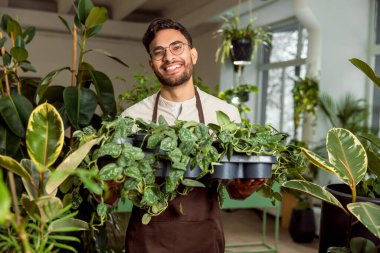 Çiçekçide çalışıyorum. Gülümseyen genç adam, aşağıdaki dükkânda mutlu ve mutlu görünüyor.