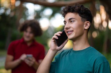 Bağlandı. Ellerinde telefon olan gençler parkta birlikte vakit geçiriyorlar.