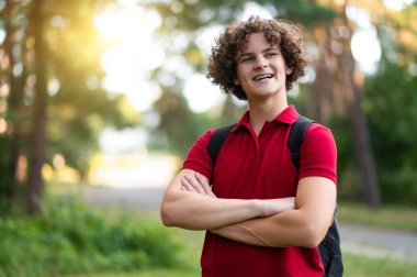 Kendine güven. Kırmızı tişörtlü genç çapraz kollu ve kendinden emin görünüyor.