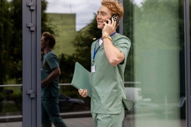 Kafkas tıp çalışanı hasta geçmişini dosyadan okuyor ve modern kliniğin dışında cep telefonuyla konuşuyor.