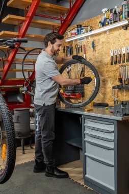 Erkek bisiklet teknisyeni eldiven takıyor. Tamir atölyesinde dağ bisikletinin fren sistemini tamir ediyor.