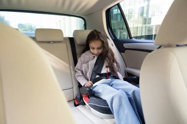 Güvenli sürüş. Koyu renk saçlı tatlı kız emniyet kemerini takmış arabada oturuyor.