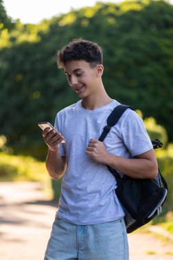 İletişim. Parkta elinde telefon olan esmer bir genç.