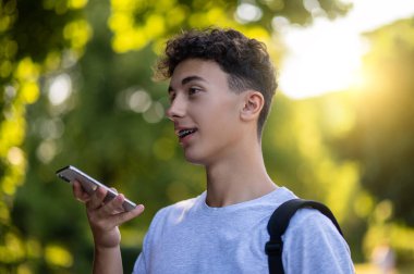 İletişim. Parkta elinde telefon olan esmer bir genç.