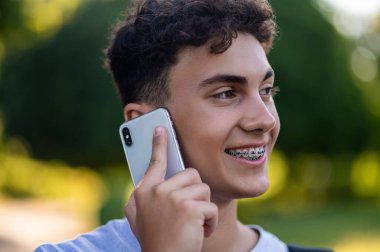 İletişim. Parkta elinde telefon olan esmer bir genç.