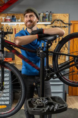 Garajda yeşil bere takan bisiklet tamircisi ve mavi polo teftiş bisikleti