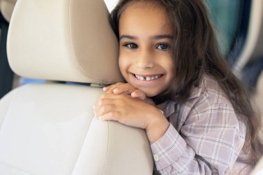 Neşeli çocuk. Sevimli bir kız bakıcıda oturuyor, keyifli ve neşeli görünüyor.