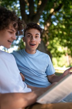 Kitap okuyordum. Parkta iki genç ders için hazırlanıyor ve kitap okuyor.