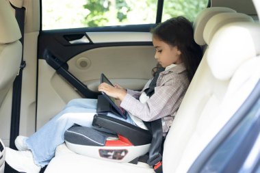 Cihazla oynuyorum. Koyu renk saçlı tatlı kız bir bakımda oturuyor ve bir aletle oynuyor.