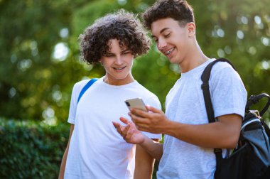 Gençler. İki genç birlikte vakit geçiriyorlar ve telefonda bir şeyler izliyorlar.
