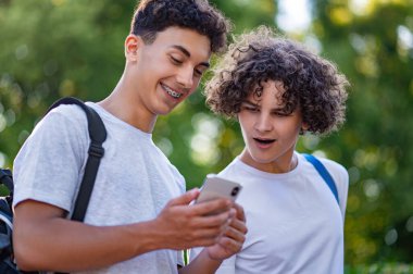 Gençler. İki genç birlikte vakit geçiriyorlar ve telefonda bir şeyler izliyorlar.
