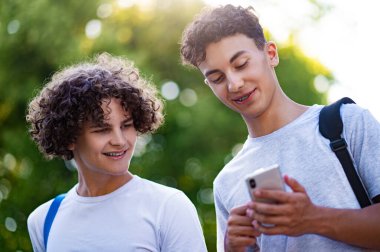 Gençler. İki genç birlikte vakit geçiriyorlar ve telefonda bir şeyler izliyorlar.