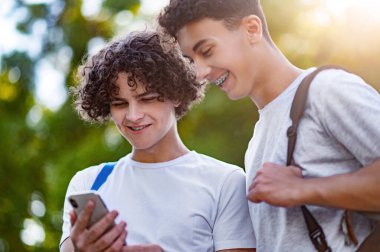 Gençler. İki genç birlikte vakit geçiriyorlar ve telefonda bir şeyler izliyorlar.