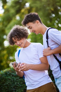 Gençler. İki genç birlikte vakit geçiriyorlar ve telefonda bir şeyler izliyorlar.