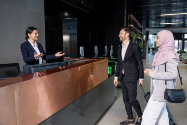 Resepsiyonda. Resepsiyonda durup resepsiyonistle konuşan hoş bir çift.