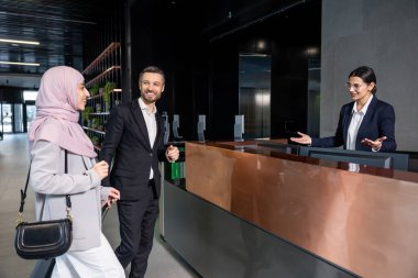 Resepsiyonda. Resepsiyonda durup resepsiyonistle konuşan hoş bir çift.