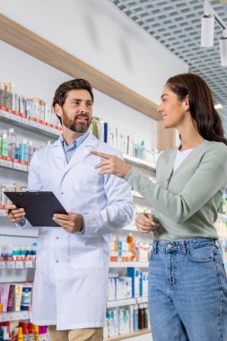 Bir müşteriyle görüşme. Erkek eczacı bir kadınla konuşuyor ve notlar alıyor.