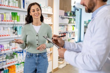 Bir müşteriyle görüşme. Erkek eczacı bir kadınla konuşuyor ve notlar alıyor.