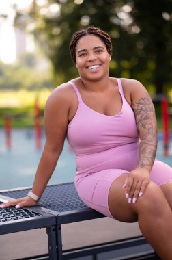 Antrenmandan sonra dinleniyorum. Pembe spor kıyafetli genç bir kadın antrenmandan sonra dinleniyor.