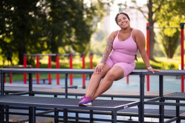 Antrenmandan sonra dinleniyorum. Pembe spor kıyafetli genç bir kadın antrenmandan sonra dinleniyor.