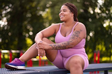 Antrenmandan sonra dinleniyorum. Pembe spor kıyafetli genç bir kadın antrenmandan sonra dinleniyor.