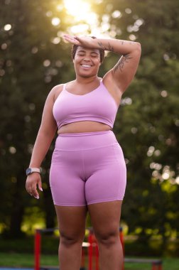 Antrenmandan sonra. Ayrıca pembe tişörtlü, kısa şortlu, spor yaptıktan sonra yorgun hisseden bir kadın.