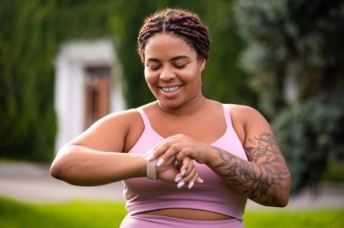 Nabız kontrolü. Kolunda dövmesi olan genç bir kadın akıllı koluna bakıyor.