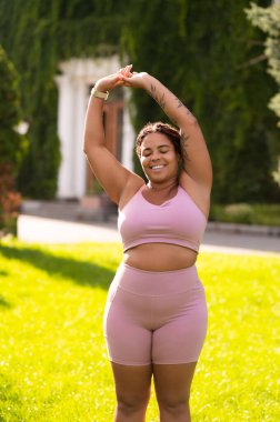 Sabah esnemesi. Pembe spor kıyafetli kadın esneme hareketleri yapıyor ve rahatlamış görünüyor.