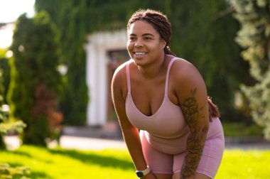 Sabah esnemesi. Pembe spor kıyafetli kadın esneme hareketleri yapıyor ve rahatlamış görünüyor.